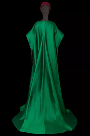 Maniquí visto desde atrás vestido con una capa verde